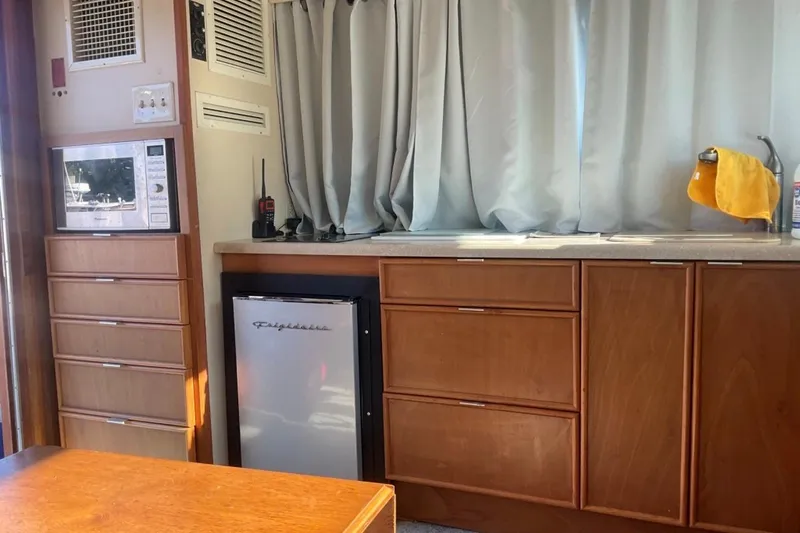 Slide: The Image of Interior of 1985 Hatteras 36 Convertible with microwave, fridge, and wooden cabinetry. - 6
