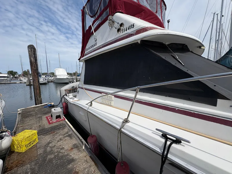 Slide: The Image of 1986 Trojan 32 Sedan boat docked at marina, featuring red canopy and white hull. - 15