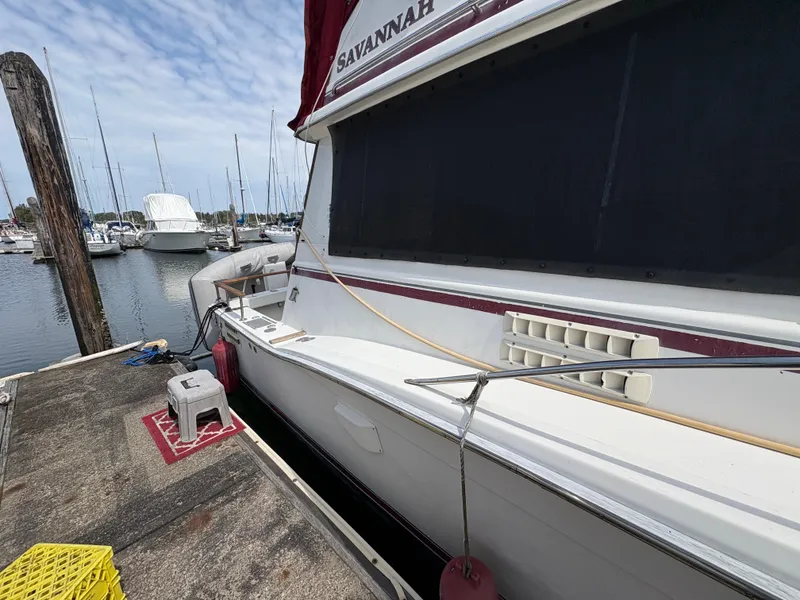 Slide: The Image of 1986 Trojan 32 Sedan docked at marina, side view with nearby boats. - 16