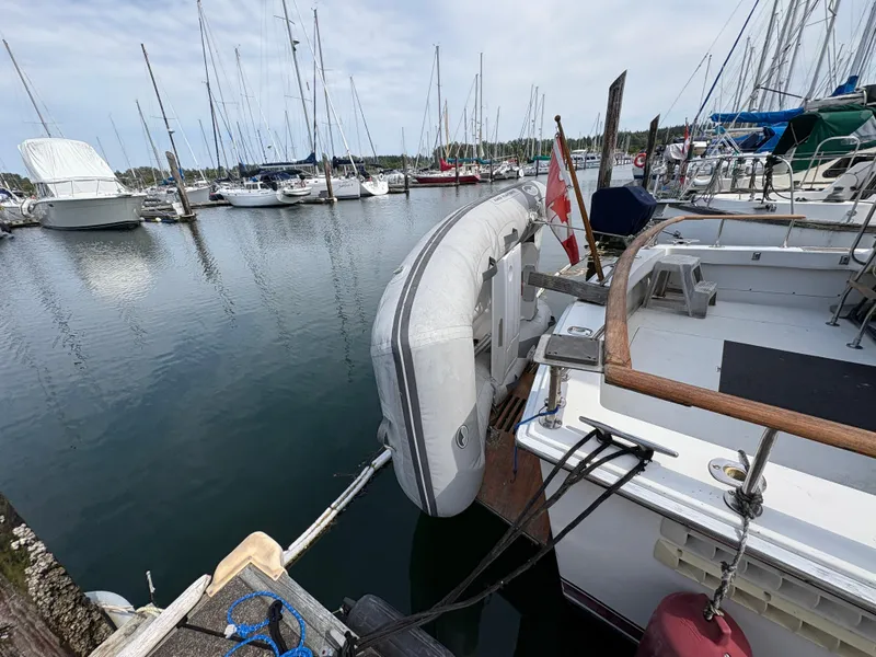 Slide: The Image of 1986 Trojan 32 Sedan docked with inflatable boat, surrounded by marina and sailboats. - 19