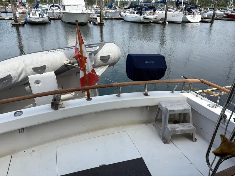 Slide: The Image of 1986 Trojan 32 Sedan boat docked with Canadian flag and inflatable dinghy. - 20