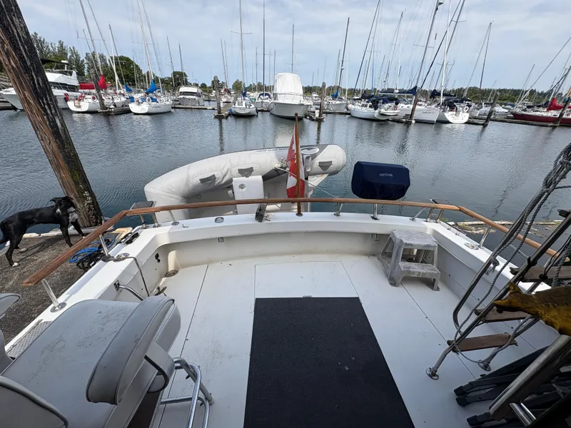 Slide: The Image of 1986 Trojan 32 Sedan at marina, surrounded by sailboats, with inflatable dinghy and docked dog. - 21