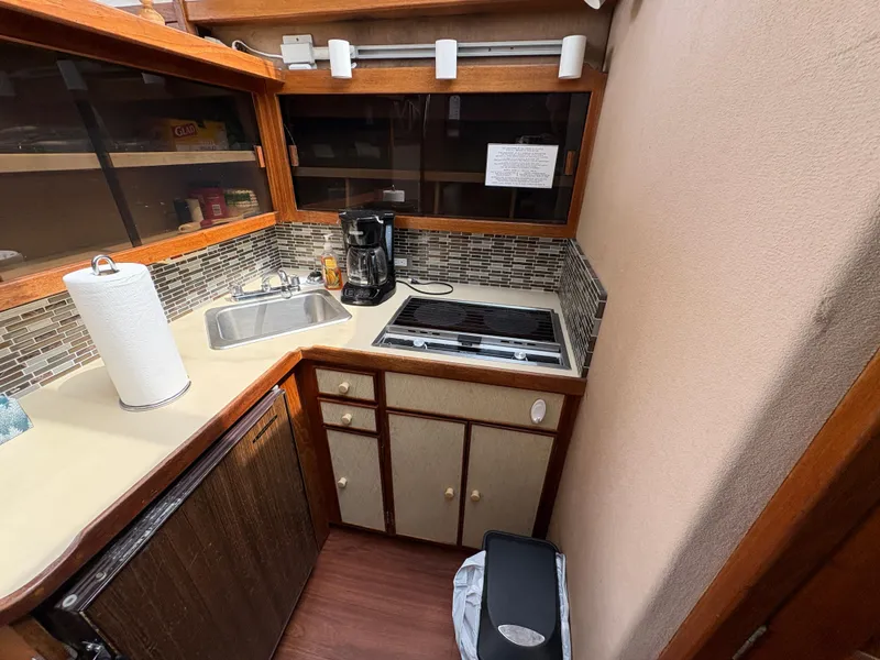 Slide: The Image of Compact kitchen in a 1986 Trojan 32 Sedan boat with stove, sink, and coffee maker. - 42