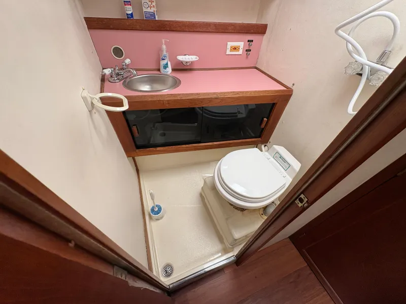 Slide: The Image of Compact bathroom in a 1986 Trojan 32 Sedan boat, featuring a toilet and sink. - 44