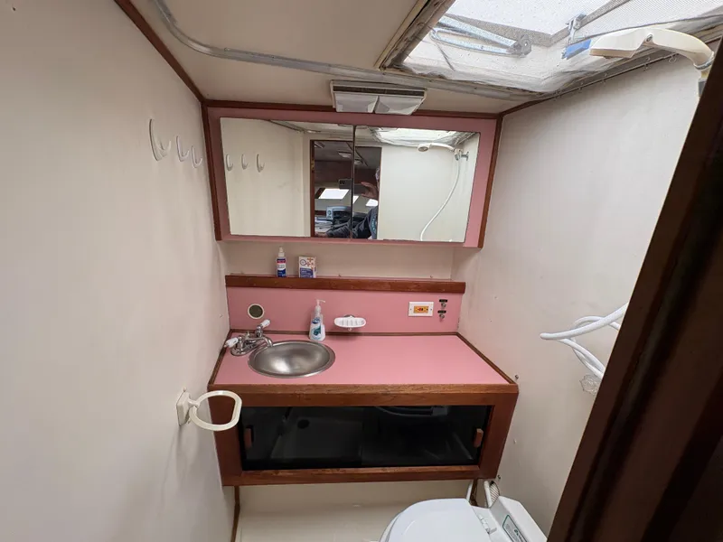Slide: The Image of 1986 Trojan 32 Sedan bathroom with pink countertop, sink, mirror, and skylight. - 47
