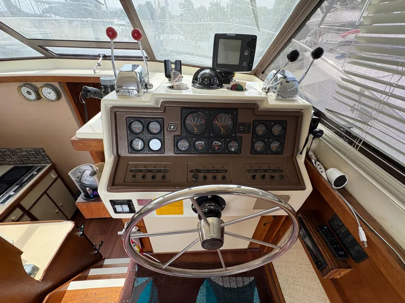Slide: The Image of 1986 Trojan 32 Sedan boat helm with gauges, steering wheel, and navigation controls. - 49