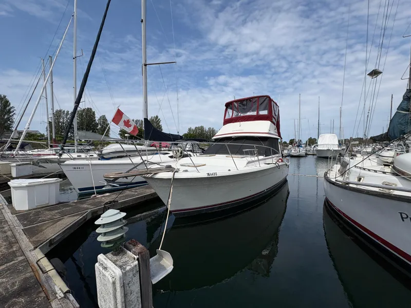 Slide: The Image of 1986 Trojan 32 Sedan boat docked in marina with Canadian flag. - 5