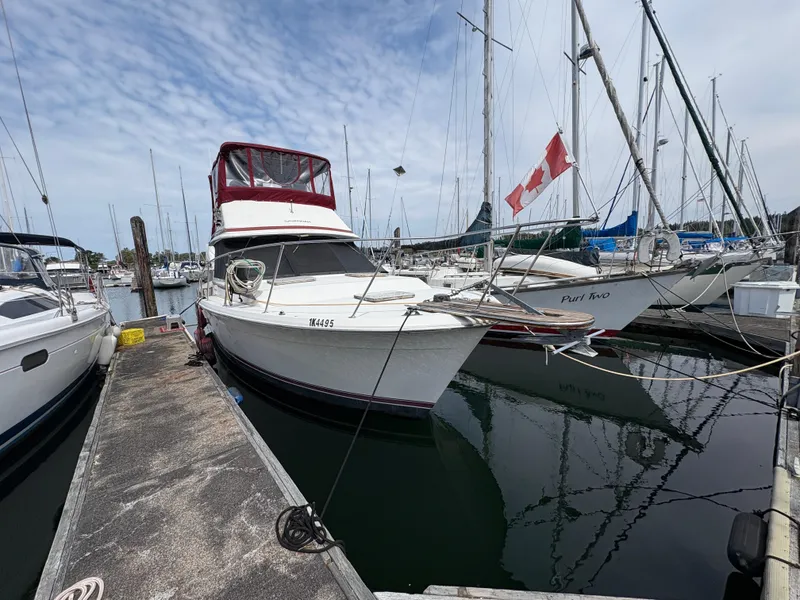 Slide: The Image of 1986 Trojan 32 Sedan boat docked in marina with Canadian flag. - 9