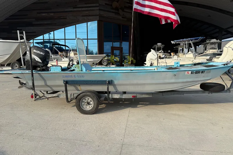 Slide: The Image of 1990 Duracraft 1860 DC boat on trailer with Suzuki outboard motor, American flag in background. - 10