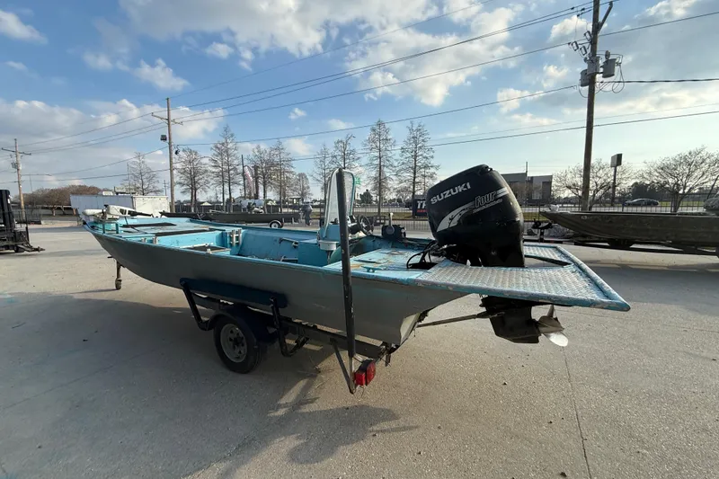 Slide: The Image of 1990 Duracraft 1860 DC boat with Suzuki outboard motor on trailer, parked outdoors. - 12