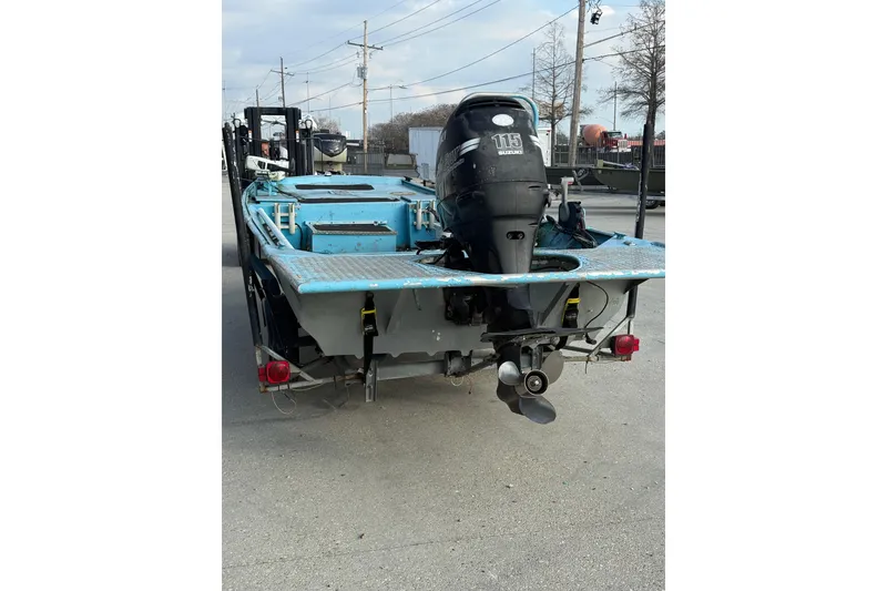 Slide: The Image of 1990 Duracraft 1860 DC boat with Suzuki 115 outboard motor, parked on a trailer. - 16