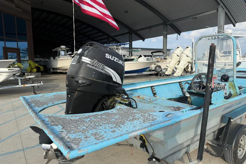 Slide: The Image of 1990 Duracraft 1860 DC boat with Suzuki outboard motor, parked under a metal roof. - 3