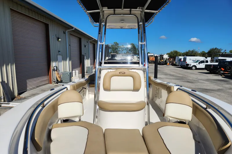 Slide: The Image of 2020 Key West 203 FS boat interior with beige seating and T-top, parked outdoors. - 6