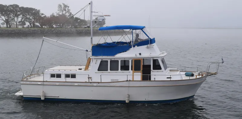 Slide: The Image of 1974 Californian 42 LRC boat on calm water with blue canopy. - 10