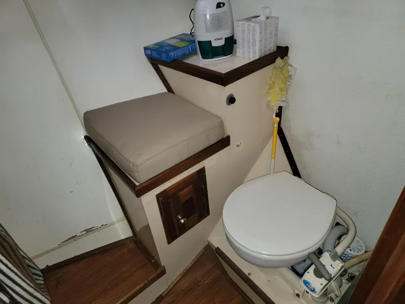Slide: The Image of 1974 Californian 42 LRC boat bathroom with toilet, cushioned seat, and cleaning supplies. - 12