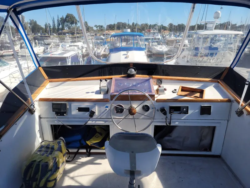 Slide: The Image of 1974 Californian 42 LRC boat helm with steering wheel, marina view, and nautical equipment. - 17