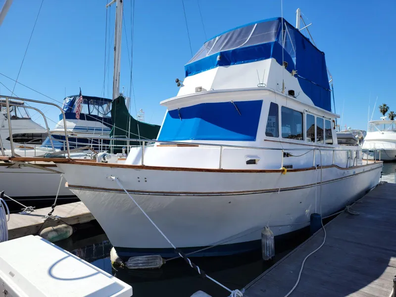 Slide: The Image of 1974 Californian 42 LRC yacht docked at marina, featuring blue canopy and white hull. - 19