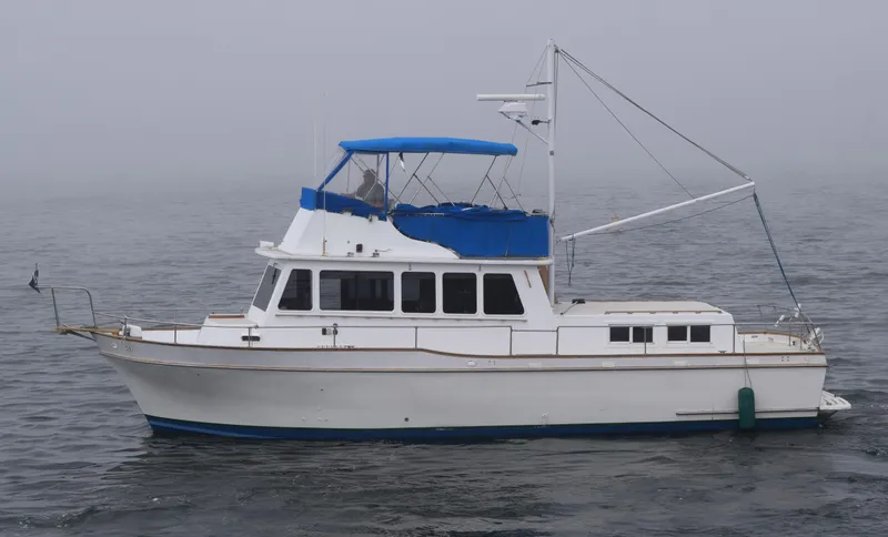 Slide: The Image of 1974 Californian 42 LRC yacht on misty water, featuring blue canopy and classic design. - 20