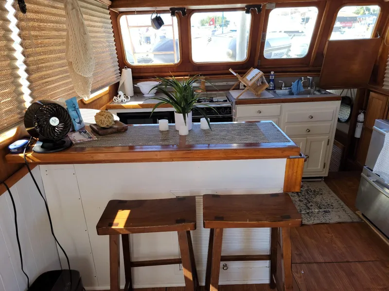 Slide: The Image of 1974 Californian 42 LRC boat interior with kitchen, bar stools, and wooden accents. - 4