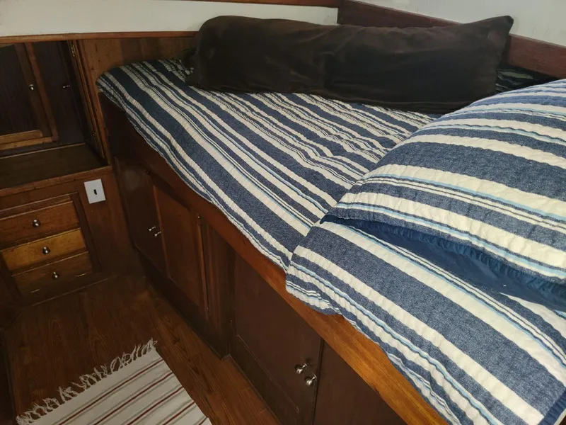 Slide: The Image of Cozy cabin interior of 1974 Californian 42 LRC with striped bedding and wooden storage. - 6