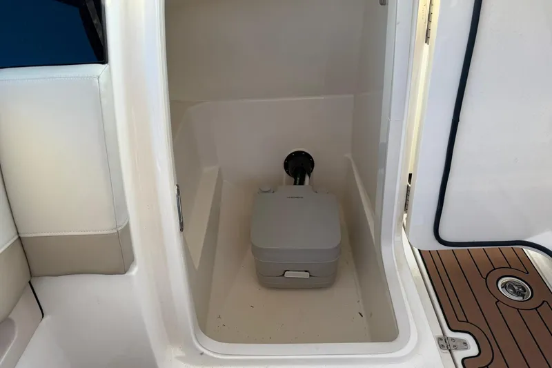 Slide: The Image of Interior of 2022 Boston Whaler 240 Vantage showing compact marine toilet. - 12