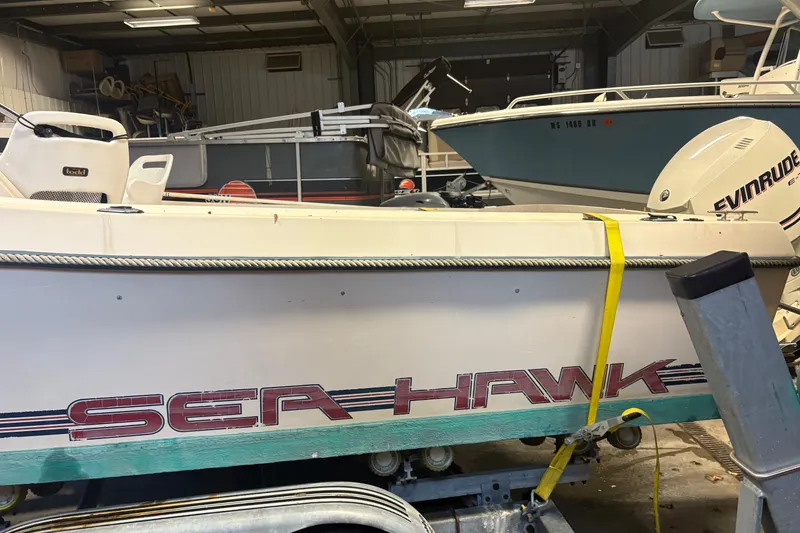 Slide: The Image of 1987 Sea Hawk 215 boat in storage, featuring Evinrude outboard motor. - 2