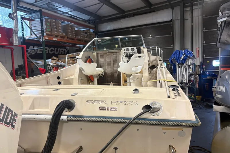 Slide: The Image of 1987 Sea Hawk 215 boat in a workshop, featuring dual seats and control panel. - 4