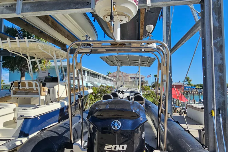 Slide: The Image of 2007 Ribcraft 6.5 boat with Yamaha 200 engine, docked under a metal canopy. - 14