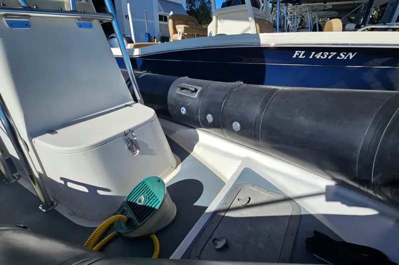 Slide: The Image of 2007 Ribcraft 6.5 boat interior with seating and equipment, docked beside another vessel. - 6