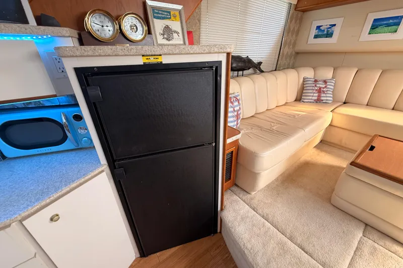 Slide: The Image of 1998 Silverton 40 Convertible interior with beige seating, black fridge, and blue microwave. - 50