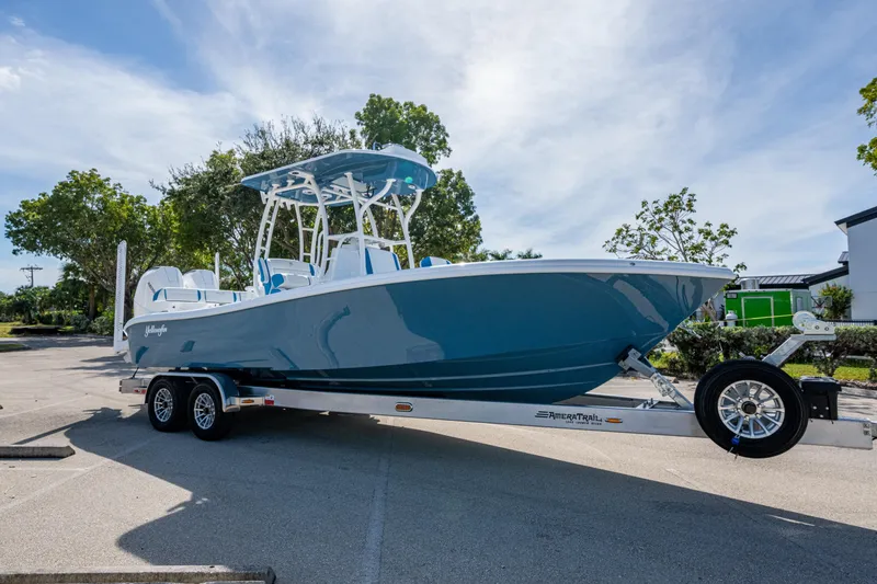 The Image of 2026 Yellowfin 26 Hybrid boat on trailer, parked outdoors under clear sky. - 0