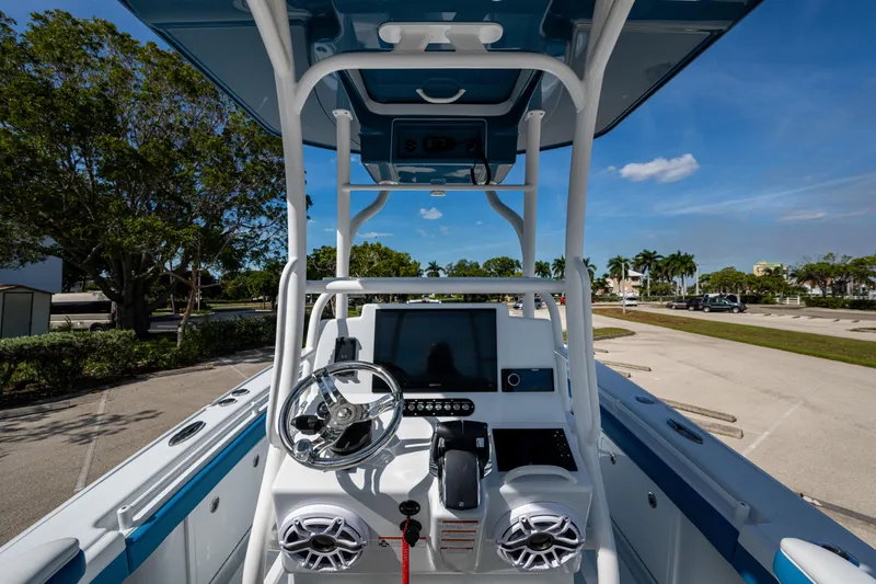 Slide: The Image of 2026 Yellowfin 26 Hybrid boat console with steering wheel and electronics under clear blue sky. - 14