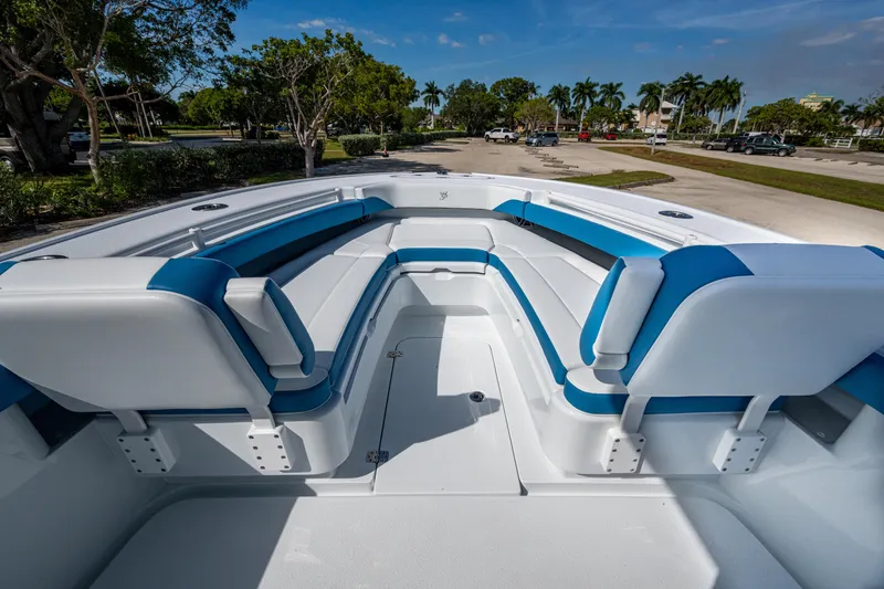 Slide: The Image of 2026 Yellowfin 26 Hybrid boat interior with blue and white seating, parked outdoors. - 17