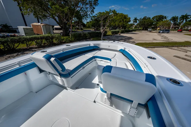 Slide: The Image of 2026 Yellowfin 26 Hybrid boat interior with blue and white seating, parked outdoors. - 18