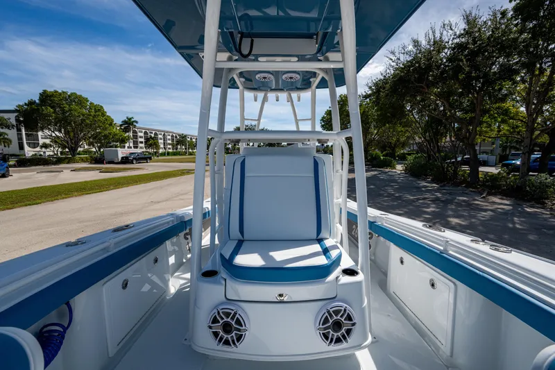 Slide: The Image of 2026 Yellowfin 26 Hybrid boat interior with blue and white seating, parked outdoors. - 19