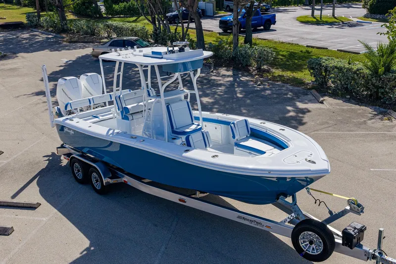Slide: The Image of 2026 Yellowfin 26 Hybrid boat on trailer in parking lot, blue and white design. - 2
