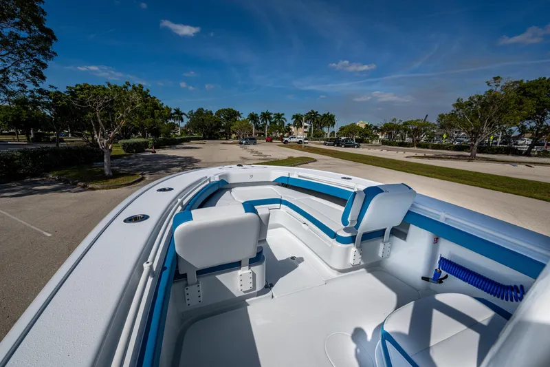 Slide: The Image of 2026 Yellowfin 26 Hybrid boat interior with blue and white seating, parked outdoors. - 21