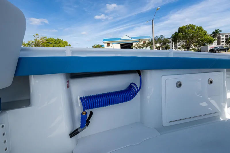 Slide: The Image of 2026 Yellowfin 26 Hybrid boat interior with blue coiled hose and storage compartment. - 27