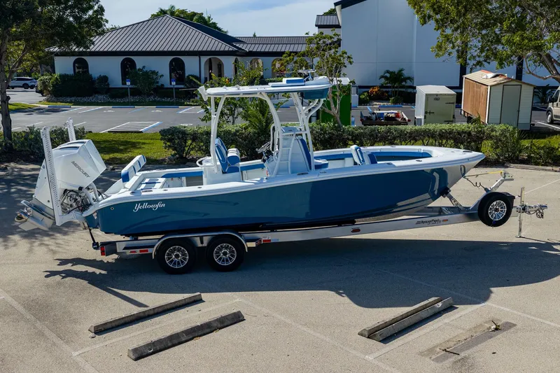 Slide: The Image of 2026 Yellowfin 26 Hybrid boat on trailer in parking lot, blue and white design. - 33