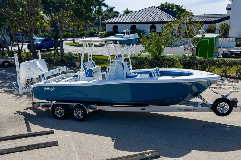 Slide: The Image of 2026 Yellowfin 26 Hybrid boat on trailer, blue and white design, parked outdoors. - 52
