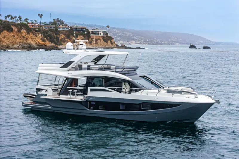 Slide: The Image of 2023 Galeon 640 Fly yacht cruising near rocky coastline under a clear sky. - 5