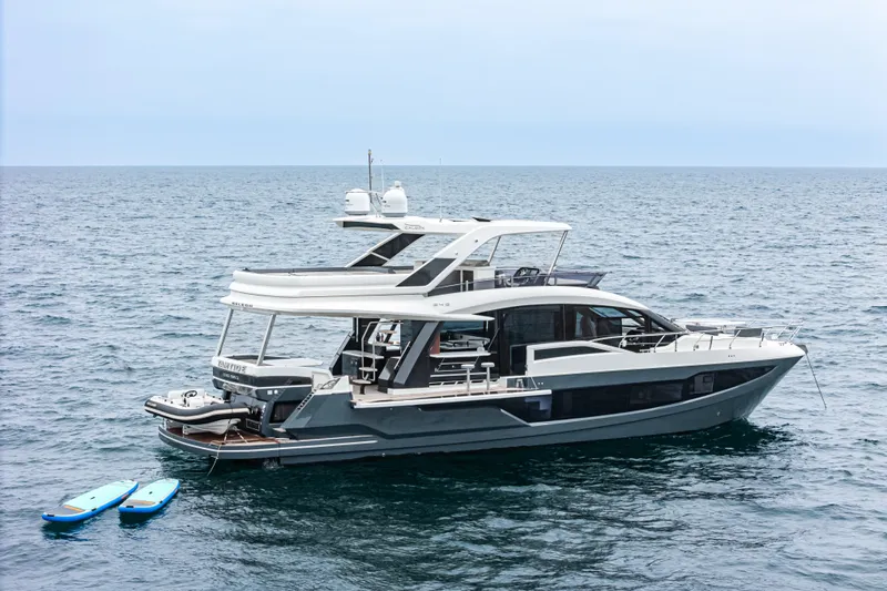 Slide: The Image of 2023 Galeon 640 Fly yacht on open sea with paddleboards nearby. - 6