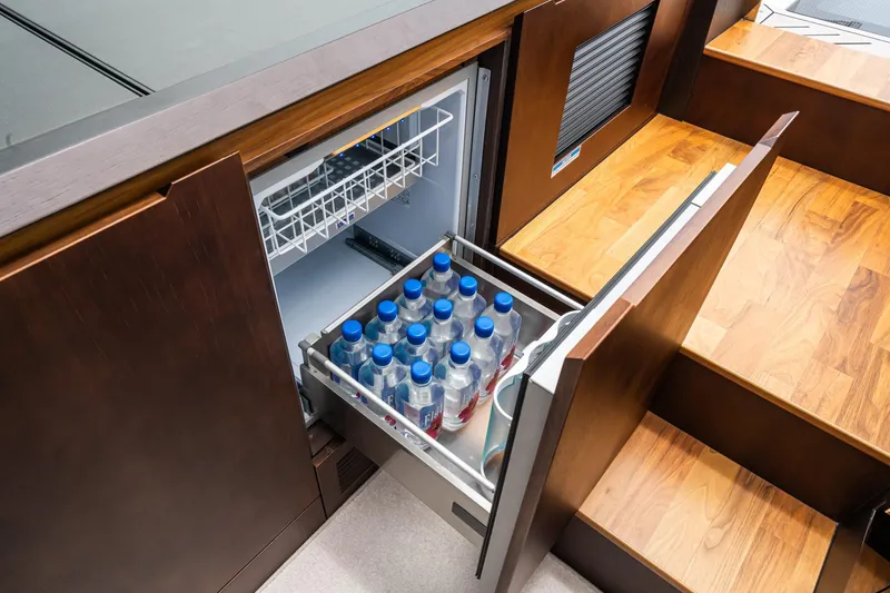 Slide: The Image of 2023 Galeon 640 Fly yacht interior with open drawer fridge stocked with water bottles. - 61
