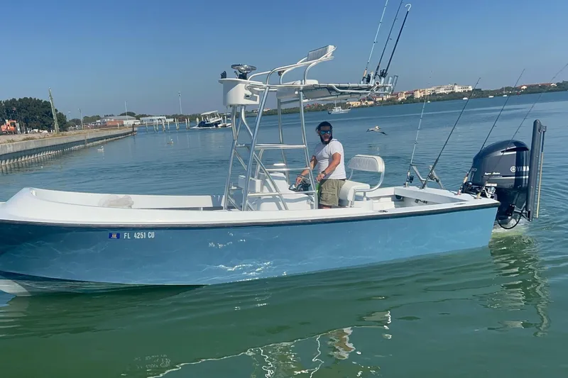 Slide: The Image of 1974 Aquasport 2400 Center Console boat on calm water, with a person steering. - 2