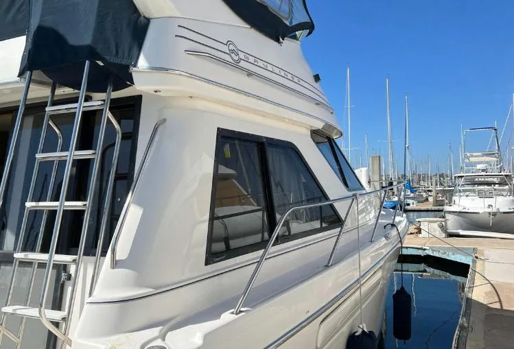Slide: The Image of 1997 Bayliner 3788 Command Bridge Motoryacht docked at marina under clear blue sky. - 3