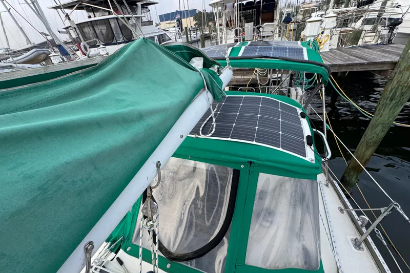 Slide: The Image of 1983 Sabre 34 sailboat with green covers and solar panels docked at a marina. - 14