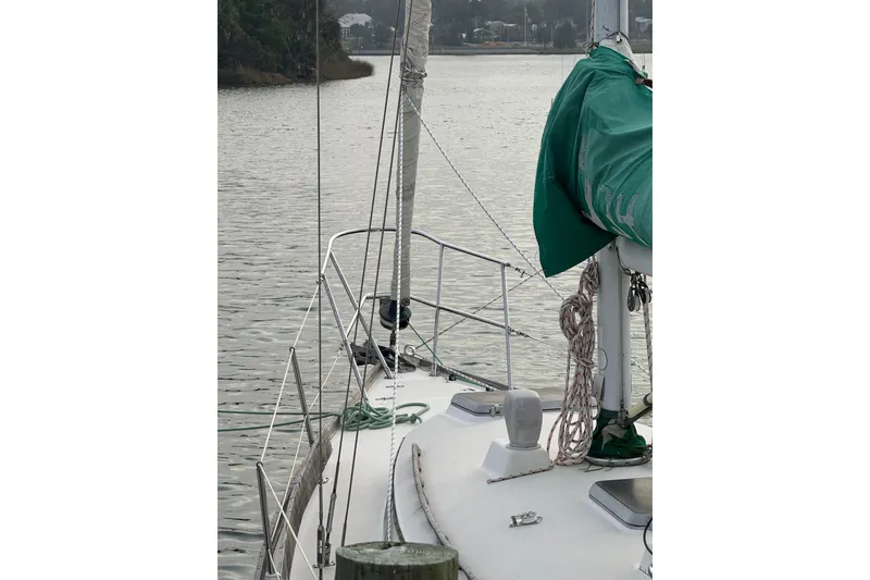 Slide: The Image of 1983 Sabre 34 sailboat docked on calm water, featuring green sail cover. - 3