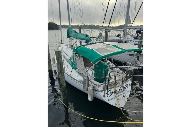 Slide: The Image of 1983 Sabre 34 sailboat docked, featuring green canvas covers and solar panels. - 5