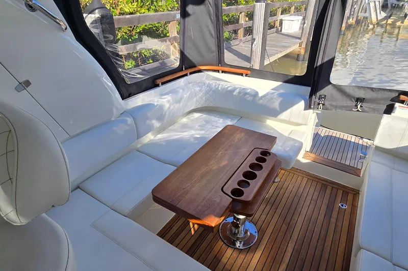 Slide: The Image of 2025 Marex 310 Sun Cruiser interior with white seating and wooden table, dockside view. - 32