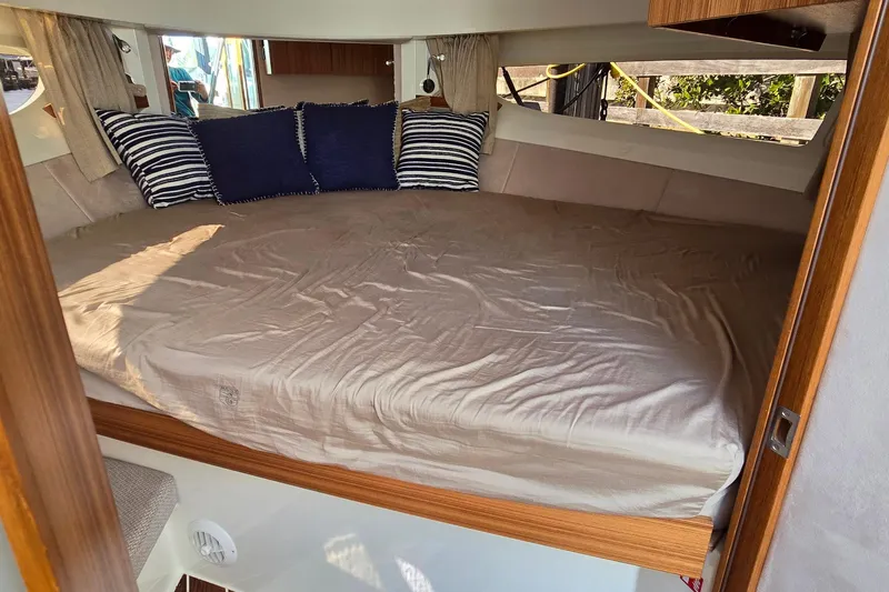 Slide: The Image of 2025 Marex 310 Sun Cruiser cabin with cozy bed and striped pillows. - 43